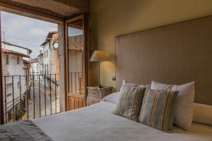 una camera da letto con un letto grande e un balcone di EL DUENDE DEL CHAFARIL a San Martín de Trevejo Altre 44 foto