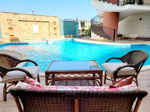 een patio met stoelen, een tafel en een zwembad bij Oasis marsa alam in Marsa Alam