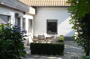 un patio con mesa y sillas junto a una casa en Holiday Home and Office Domisi'l en Wachtebeke
