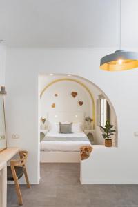 ein weißes Schlafzimmer mit einem Bett in einem Torbogen in der Unterkunft Mod Santorini Vegan Boutique Hotel in Fira