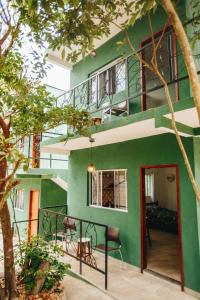 une maison verte avec une porte rouge et des chaises dans l'établissement Marília EcoHome Pipa, à Pipa