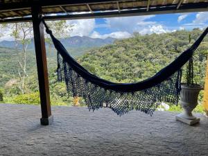a hammock on a porch with a view of the mountains at Pousada R.N.C. Nosso Paraíso in Teresópolis