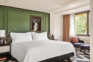 a bedroom with a large white bed and a green wall at Rosewood Villa Magna in Madrid