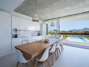 Il comprend une cuisine et une salle à manger avec une table et des chaises en bois. dans l'établissement Villa barcares, à Alcúdia
