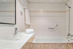 a white bathroom with a sink and a tub at BLUESEA Piscis - Adults Only in Port d'Alcudia