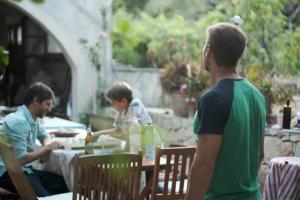 een groep mensen die aan een tafel zitten te eten bij Villa Anta house by the sea in Lithakia