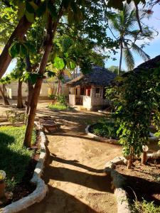 un camino que conduce a una casa con árboles y un edificio en Fontaine Garden Village, en Bwejuu