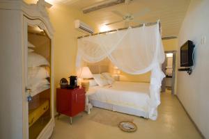 a bedroom with a white bed with a canopy at Pousada Bendito Seja in Praia do Espelho