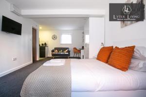 a bedroom with a large white bed with orange pillows at Leicester's Lyter living Serviced apartments Opposite Leicester Railway Station in Leicester