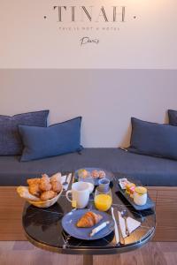 - une table basse avec des aliments pour le petit-déjeuner sur un canapé dans l'établissement Tinah Paris, Aboukir, à Paris