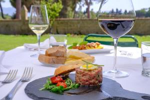a table with a plate of food and a glass of wine at Antica Fattoria La Parrina in Orbetello