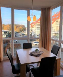 une salle à manger avec une table, des chaises et une grande fenêtre dans l'établissement Strandpark Großenbrode WR-12, à Großenbrode