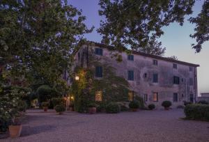 a large stone building with trees in front of it at Antica Fattoria La Parrina in Orbetello
