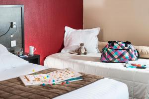 two beds with a backpack and a bag on them at Kyriad Tours - Joué-Lès-Tours in Joué-lès-Tours