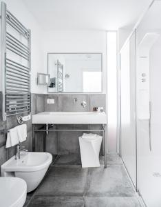 uma casa de banho branca com um lavatório e um WC em AWA Lignano Sabbiadoro em Lignano Sabbiadoro