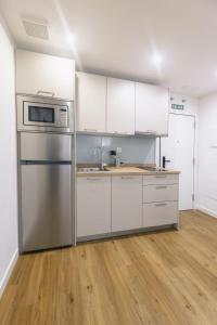 a kitchen with white cabinets and a stainless steel refrigerator at Apartamentos Centro Llanes in Llanes