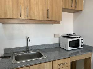 a kitchen with a sink and a microwave at Luxanos Condo Place- San Marino in Cebu City