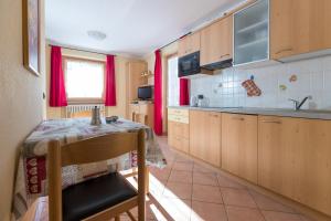 eine Küche mit einem Tisch und eine Küche mit roten Vorhängen in der Unterkunft Stefano 1 in Livigno