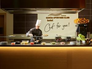 a chef standing in a kitchen preparing food at Garda Sporting Club Hotel in Riva del Garda