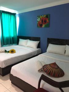 a room with two beds and a blue wall at Kapit Hotel in Kuching