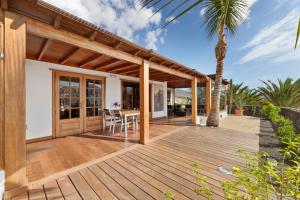 a wooden deck with a table and a palm tree at Villasal in Playa Blanca