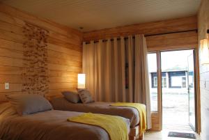 two beds in a room with wooden walls at Rumbo Sur Hotel in Villa O'Higgins