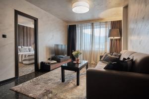 a living room with a couch and a tv and a mirror at Grand Hotel Bansko - Fitness & SPA in Bansko +74 photos