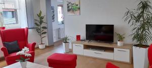 a living room with a flat screen tv and red chairs at Ferienwohnung Ortsmitte in Hilders