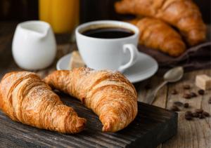a table with croissants and a cup of coffee at The Hide Away Modern Rooms in Norwood