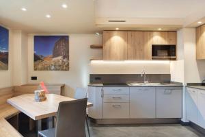 a kitchen with white cabinets and a wooden table at Rasia Residence Relax Stone in Livigno