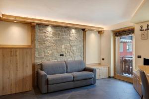 a living room with a couch and a stone wall at Rasia Residence Relax Stone in Livigno