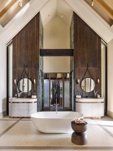 a bathroom with a tub and two sinks at JOALI Maldives in Raa Atoll