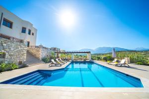 a swimming pool with chairs and a house at Iremia Luxury Villa with pool in  Episkopi (Chania)