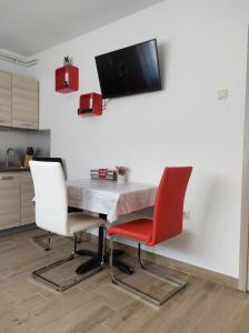een tafel met twee stoelen en een tv aan de muur bij Happy Apartment in Karlovac