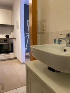 La salle de bains est pourvue d'un lavabo blanc et d'une cuisine. dans l'établissement Seeuferresidenz am Adrian Stoop, à Bad Wiessee