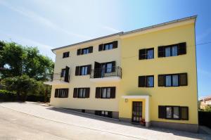 un edificio amarillo con ventanas negras y una calle en Apartments Jasmina, en Poreč