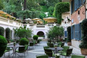 an outdoor patio with tables and chairs and umbrellas at Rocco Forte Hotel De Russie in Rome