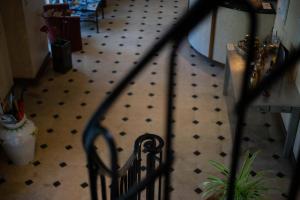 un escalier avec une balustrade en fer forgé et du carrelage dans l'établissement Auberge Bretonne, à La Roche-Bernard