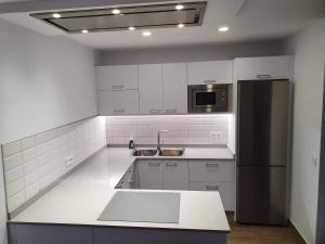 una cucina con mobili bianchi e un frigorifero nero di Casa Cetáceo a Playa Quemada