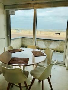 a table and chairs in a room with a large window at Zilverzand aan zee - frontaal zeezicht in Koksijde