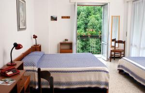 a bedroom with two beds and a table and a window at Albergo Ristorante Regina in Bognanco
