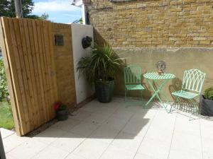 a patio with a table and chairs and a fence at Salt Yard 1 - Stylish Whitstable Cottage - Free Parking - Beach - Harbour in Whitstable