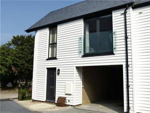 a white building with a garage with a black roof at Salt Yard 1 - Stylish Whitstable Cottage - Free Parking - Beach - Harbour in Whitstable
