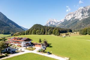 a house in a field with mountains in the background at Gästehaus Hinterponholz in Ramsau