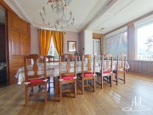 a dining room with a table with chairs and a chandelier at La demeure des tisserands in La Bresse