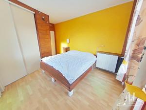 a bedroom with a bed and a yellow wall at La demeure des tisserands in La Bresse