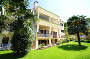 a building with palm trees in front of a yard at Apartments Jasmina in Poreč