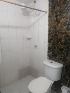 a bathroom with a white toilet and a stone wall at Casa chill out in Minca
