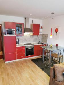 una cocina con armarios rojos y una mesa. en Fewo-Strandmaennchen, en Dahme