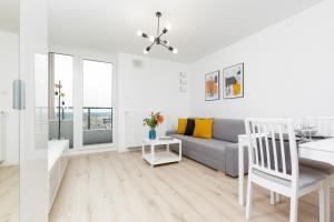 a white living room with a couch and a table at Nowa Grochowska Apartments in Warsaw